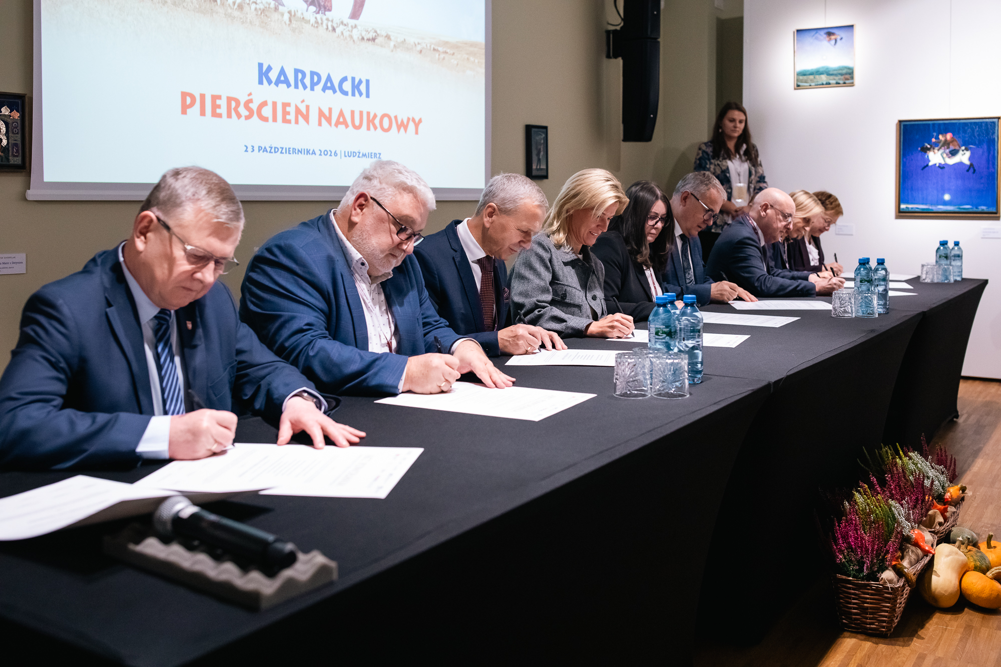 Uczestnicy siedzą przy stole i podpisują Akt Powołania Karpackiego Pierścienia Naukowego
